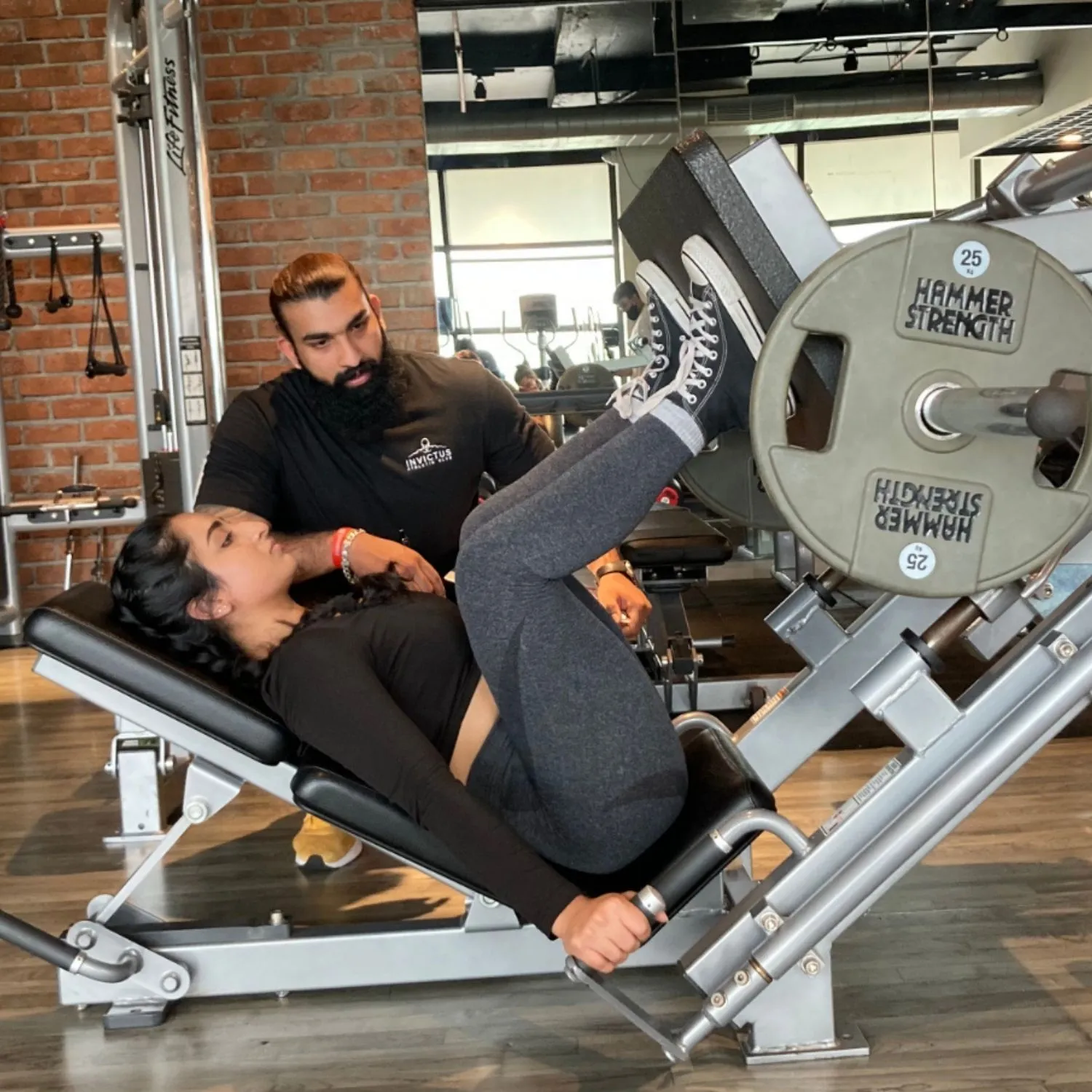 Coach spotting a client on the leg press machine