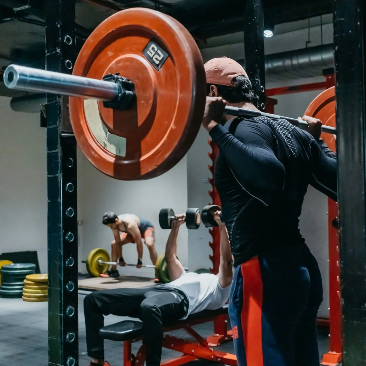 The gym floor in full swing — squat rack, bench press and deadlift all at once
