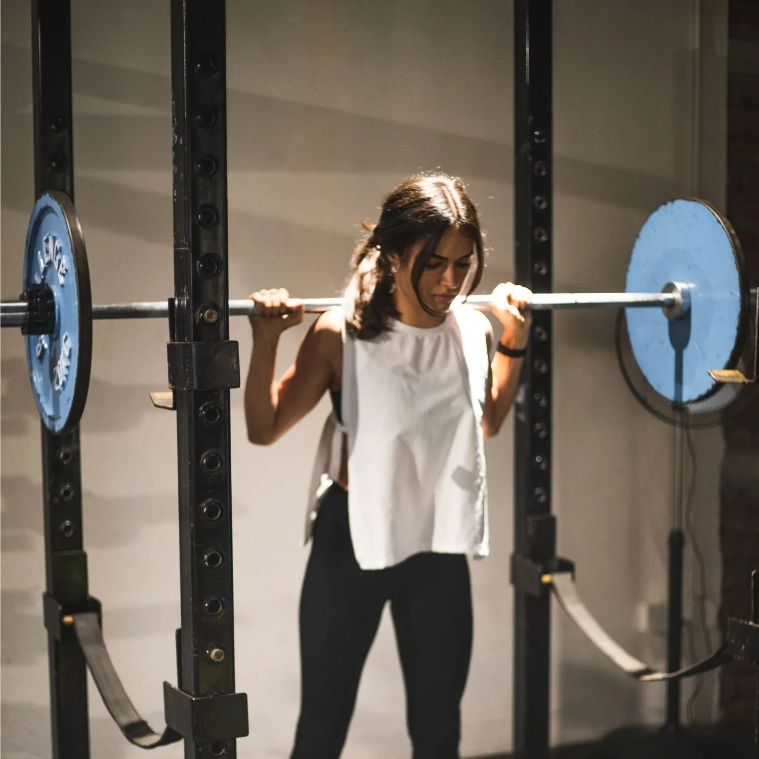 Loaded barbell back squat against the brick wall